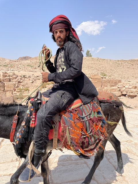       Person riding a donkey in a rocky setting.
  