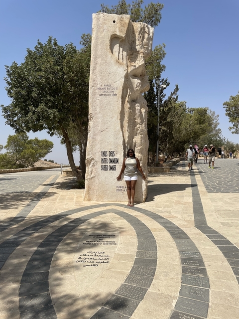       Woman standing beside a large stone with Latin inscriptions.
  
