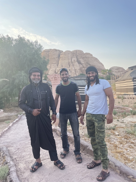       Three men posing in front of desert tents.
  