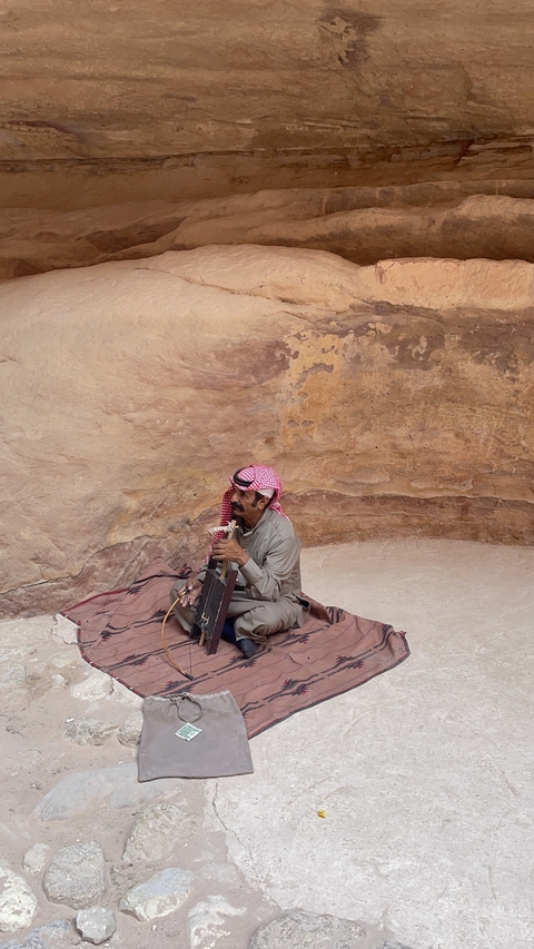       Man playing a traditional string instrument in a cave.
  