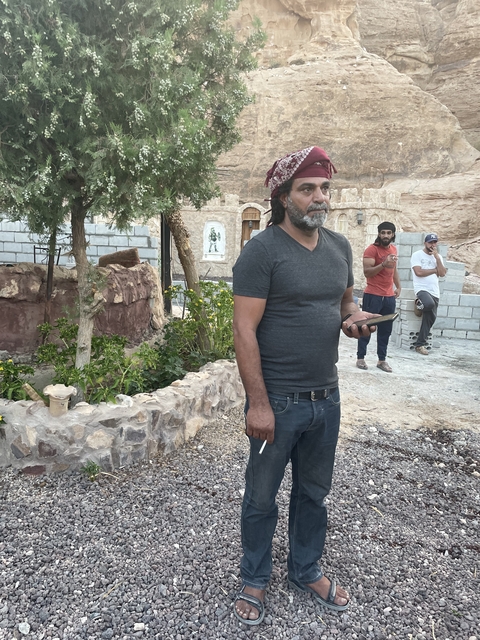       Man standing outdoors with smartphone in hand.
  