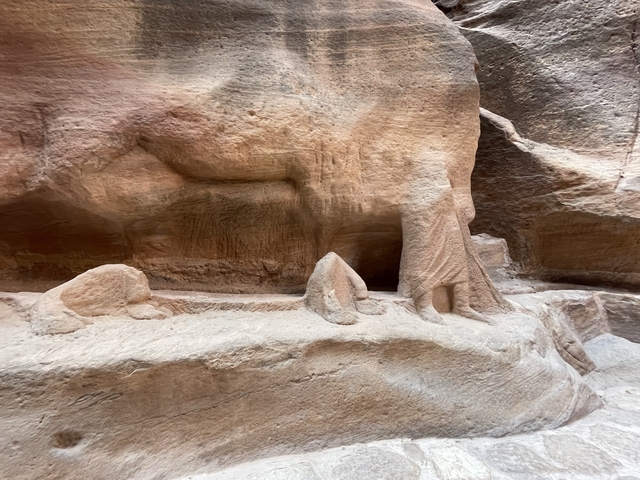       Ancient rock carvings depicting a camel and figures.
  
