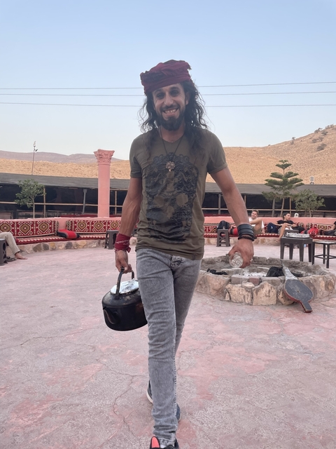 Man carrying pot in an outdoor seating area.