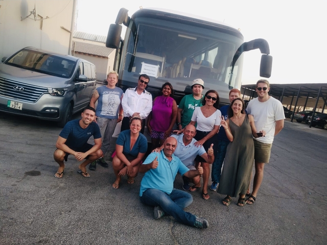       Group of people posing in front of a tour bus.
  