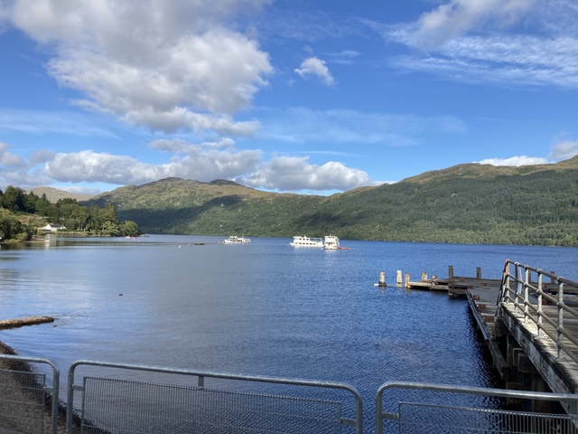       Lakeside view with boats and mountains in the distance.
  