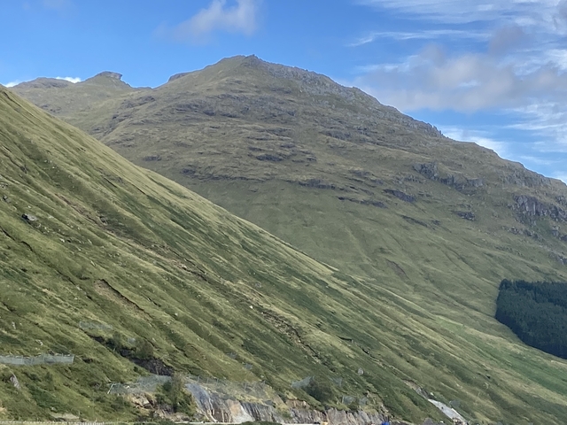 Expansive view of grassy hillside and mountains.