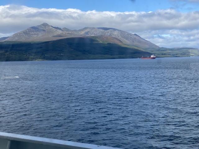       Mountain across a body of water with cargo ship passing by.
  