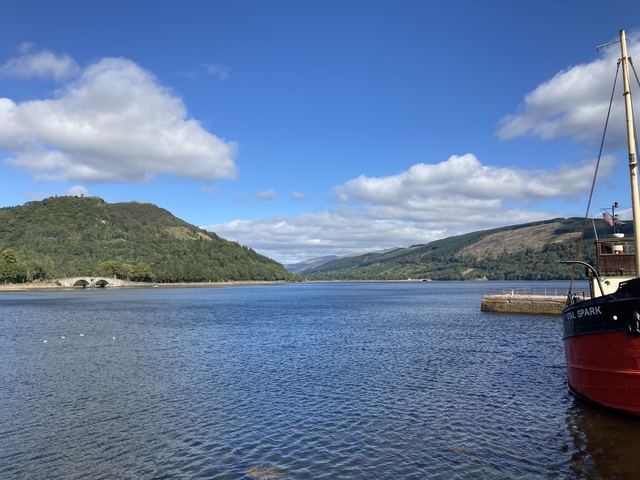 River with arch bridge and forested hills.