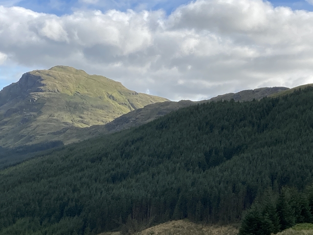       Hillside with lush greenery and cloudy sky.
  