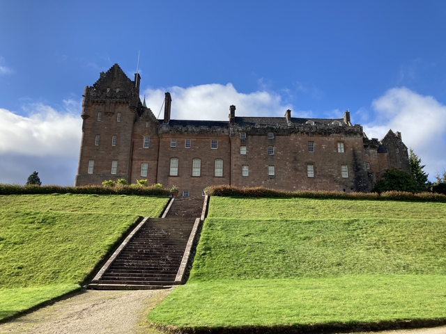       Large castle on a hill with stone stairs leading up.
  