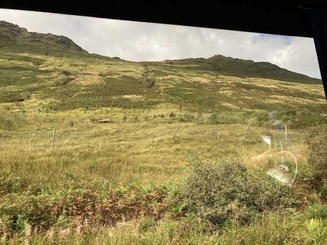 Expansive view of grassy hills with cloudy sky.