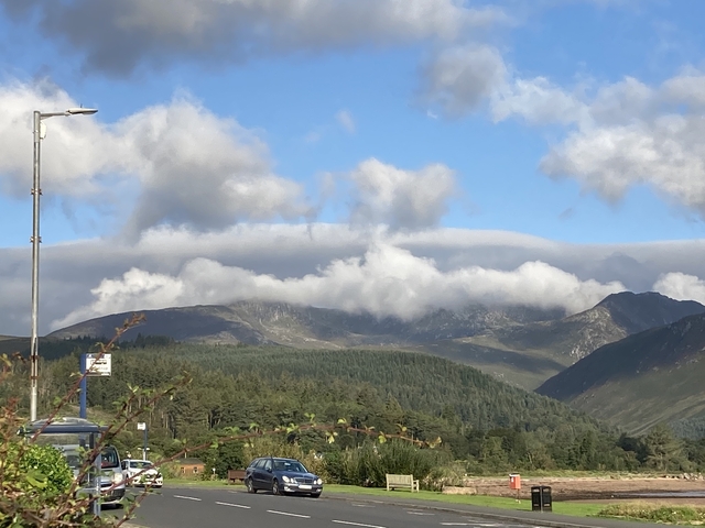       Rolling hills with clouds draping the mountain peaks.
  