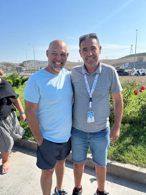 Two people posing outdoors with a sideways orientation.