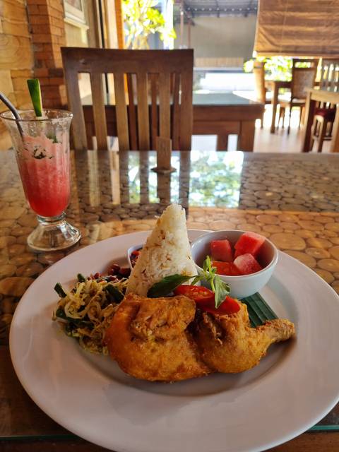       Plate of food with rice, fried chicken, vegetables, and watermelon.
  