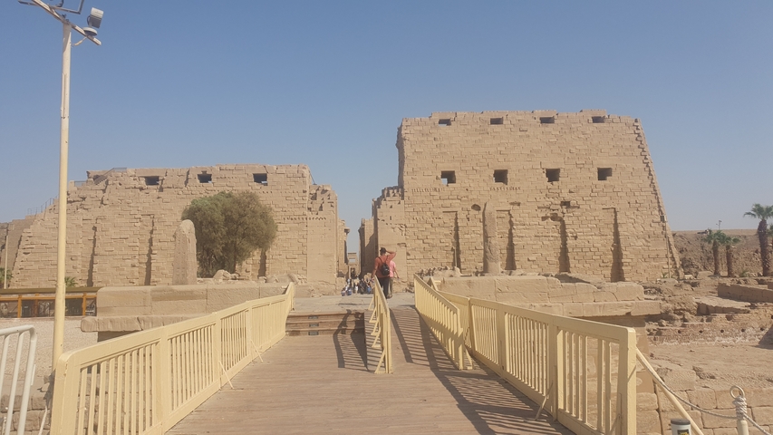 Ruins of ancient structure with stone pillars and tourists.