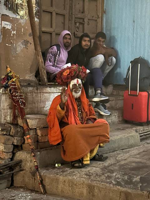 Sitting mystic with people in the background.