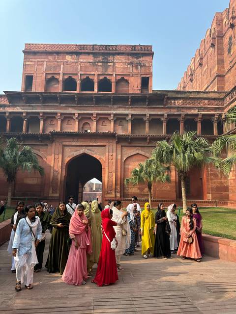 People in colorful clothes near a historic building.