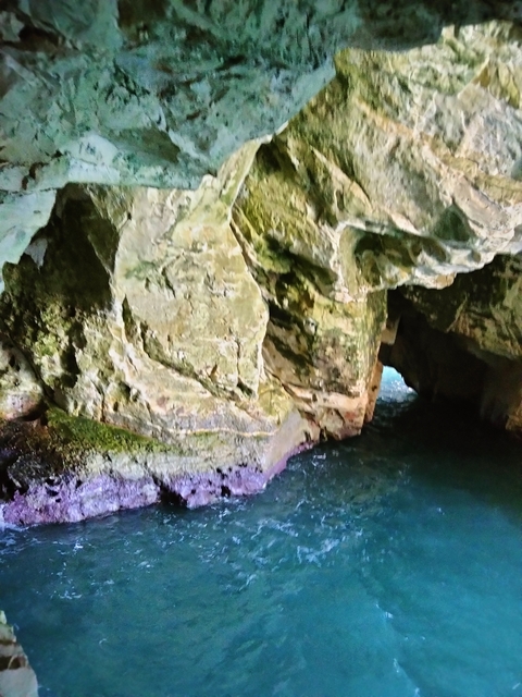       Entrance to a cave with water and rock formations.
  