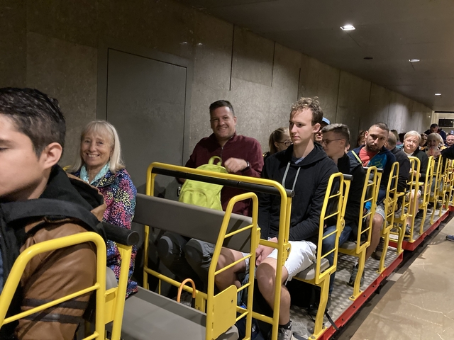 Tourists riding a small open train in a cave or tunnel.