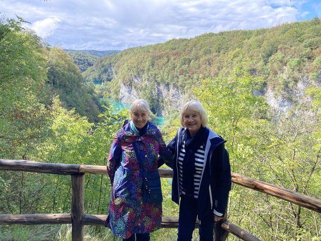 Two women posing with a lush green canyon in the background.