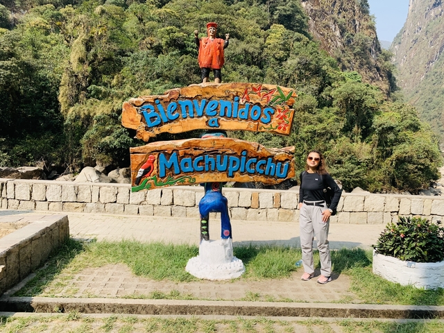 Tourist in front of a 'Bienvenidos a Machu Picchu' sign.