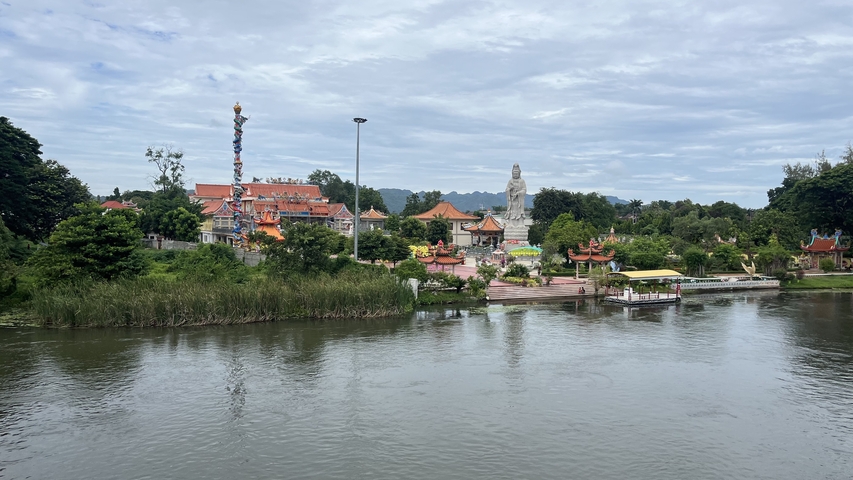 River with buildings and a large statue in the background.