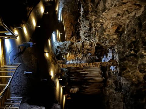 Illuminated cave interior with formations and path.