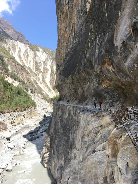 Narrow path cut into a cliffside over a river.