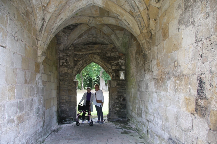 Two people standing under a stone archway.
