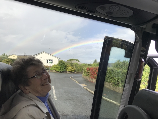       Person inside a vehicle with a rainbow visible outside.
  