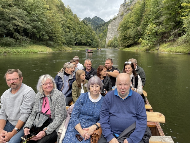 Group of people on a boat in a scenic river landscape.