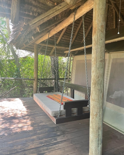       Outdoor terrace with a swing bed among trees
  