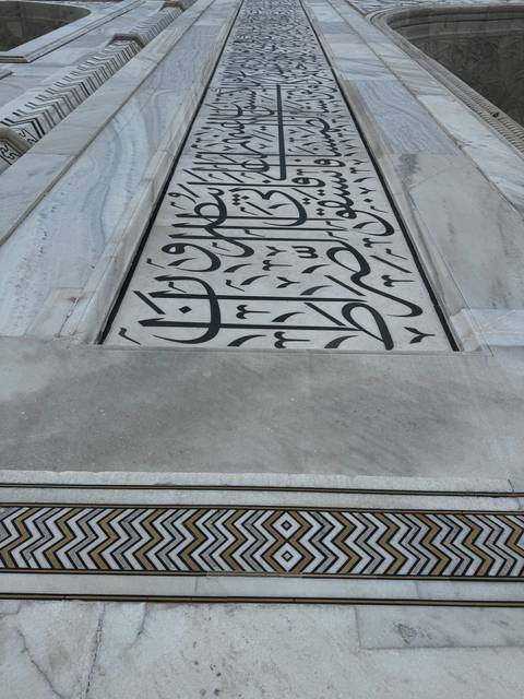 Close-up of marble wall with intricate calligraphy.