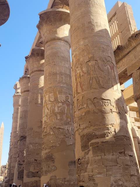 Close-up of ancient columns with hieroglyphs against a blue sky.