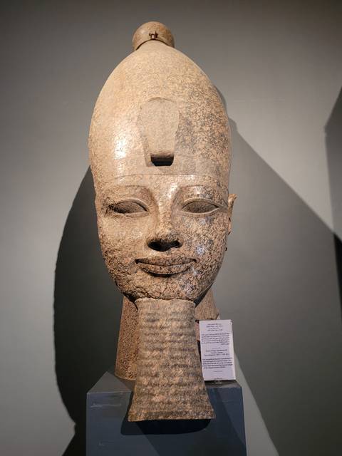 Statue of an ancient Egyptian figure in a museum setting.