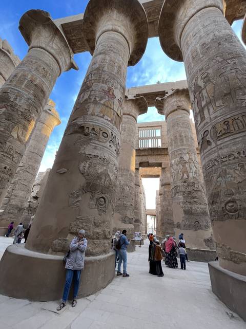 Visitors exploring columns with hieroglyphics.