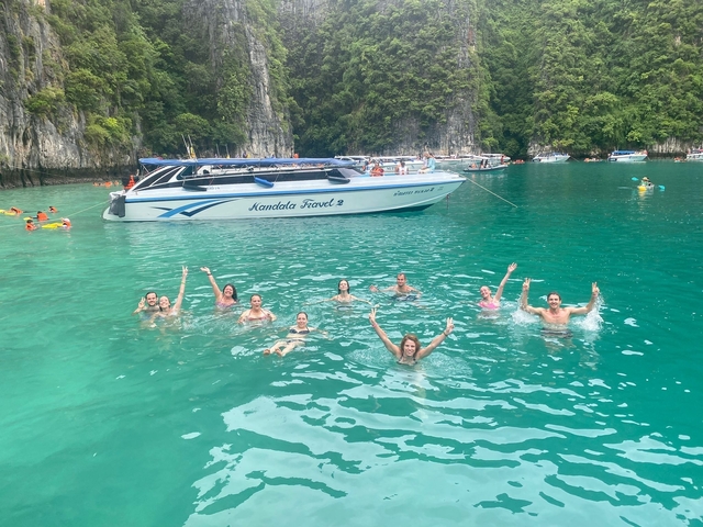 Group of people swimming in a lagoon with speedboats in the background.
