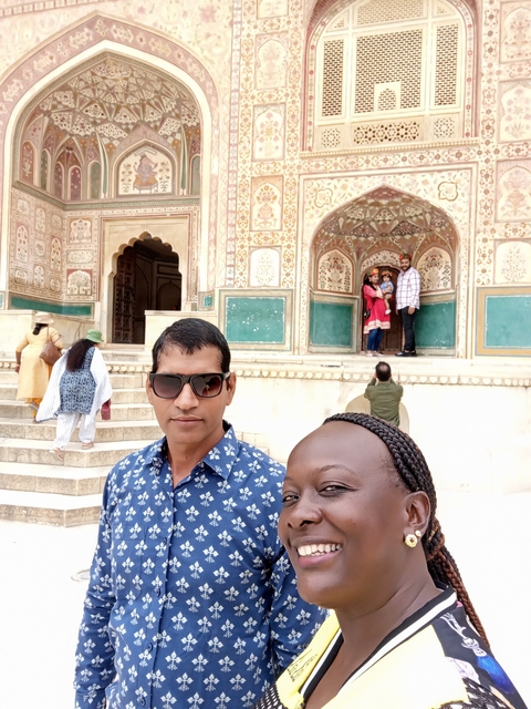       People posing in front of a historic building with intricate carvings.
  