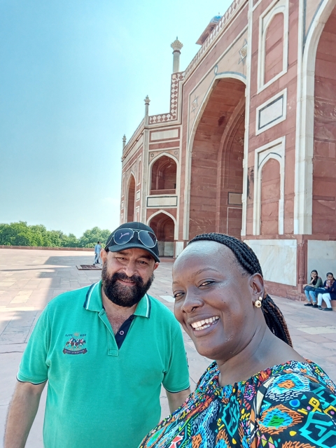       Two people posing in front of a building with arches.
  