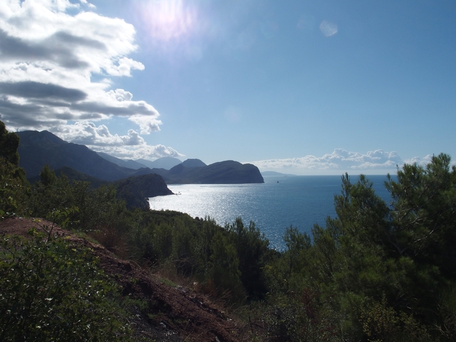 Coastal landscape with mountains, sea, and dramatic sky.