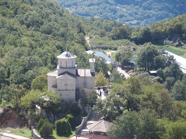 Stone church surrounded by greenery on a hillside.