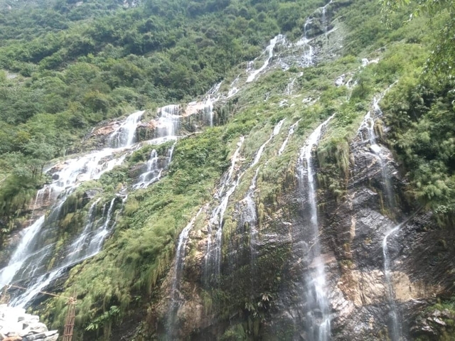       Waterfall cascading down a lush green cliff.
  
