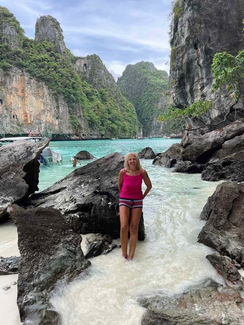 Woman standing in front of rocky cliffs and clear water.
