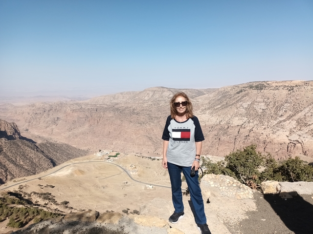 Woman posing with a mountain landscape in the background.
