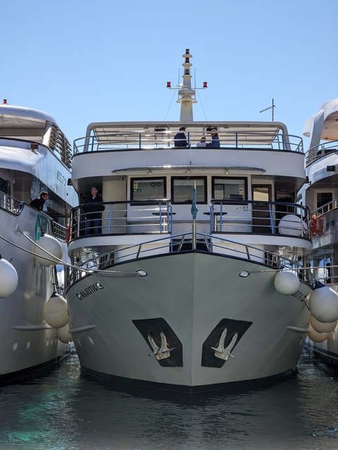      Close-up view of a yacht's front with people on the deck.
  