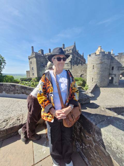       Elderly couple sitting on a castle wall.
  