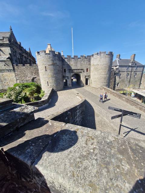       Stone castle gate with visitors inside the courtyard.
  