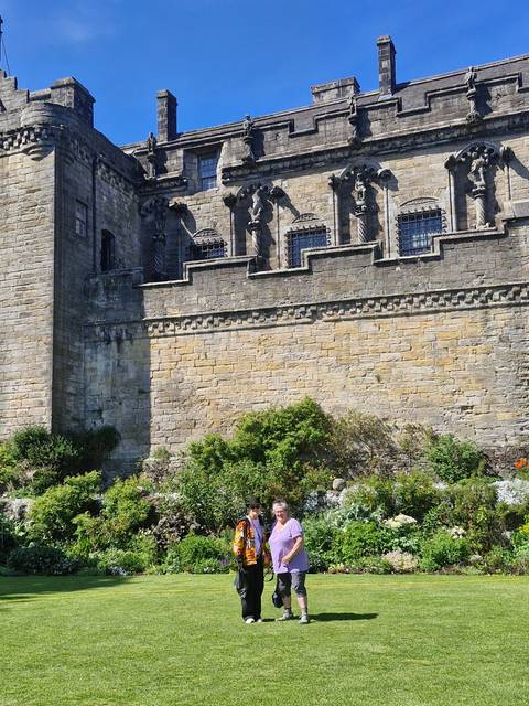       People posing in front of a historic stone building.
  