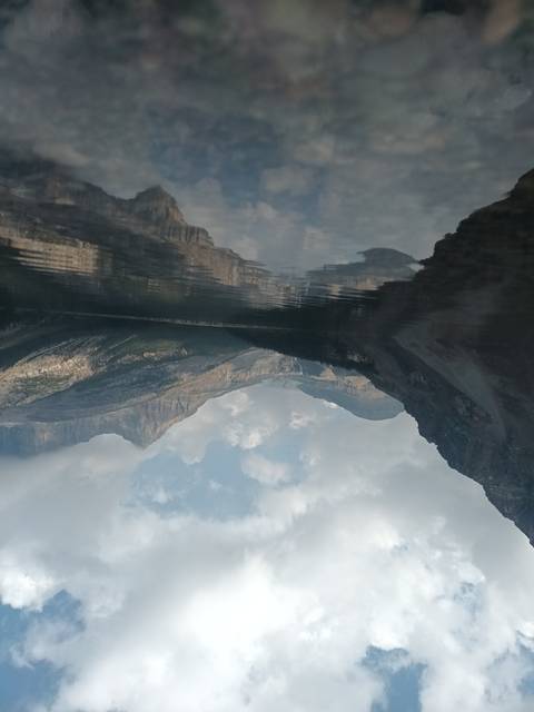 Reflection of mountains and sky in calm water.