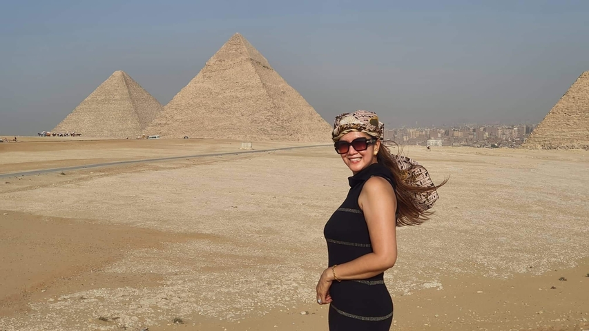 Woman posing with Giza pyramids in the background.